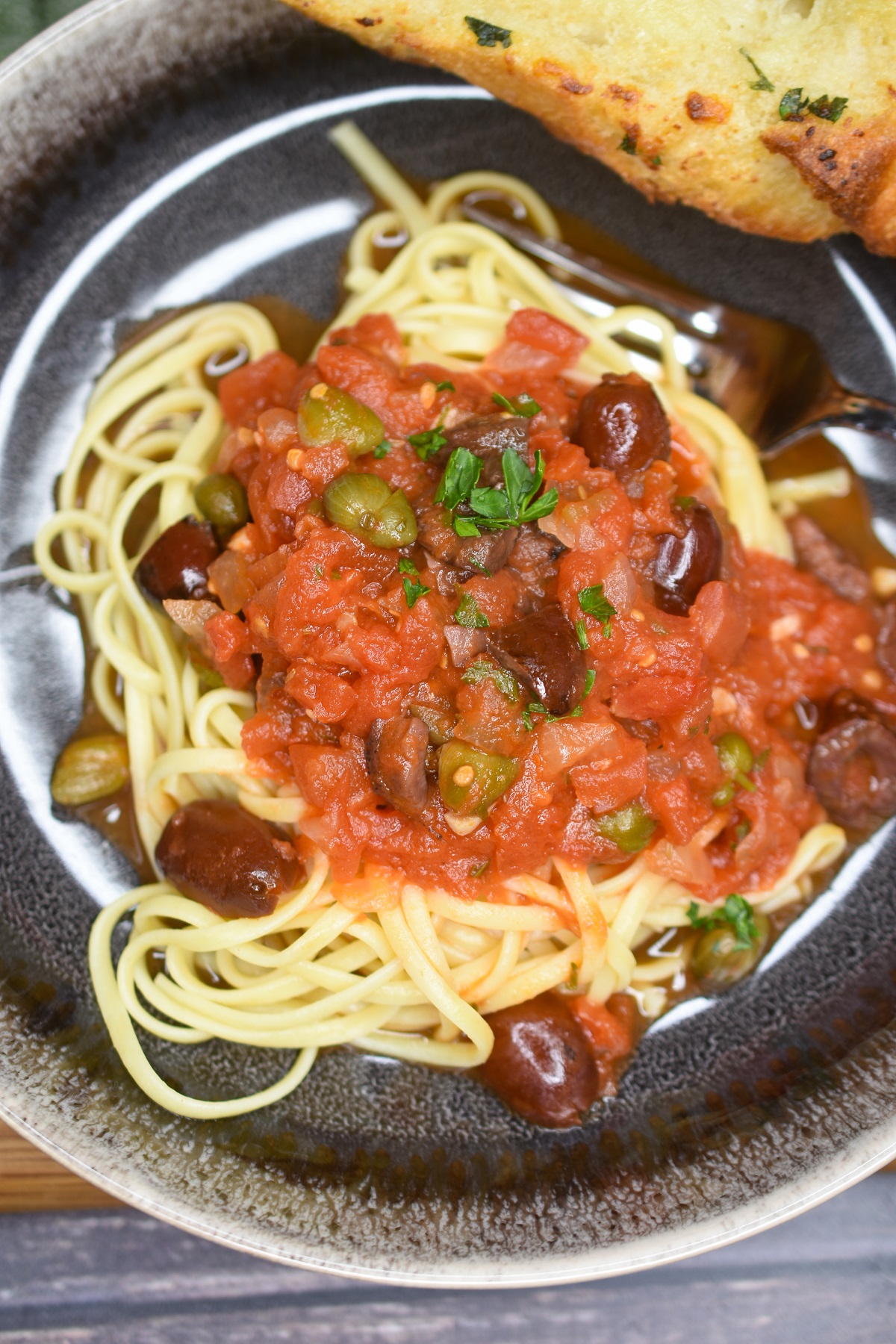 Puttanesca Sauce overtop pasta in a bowl