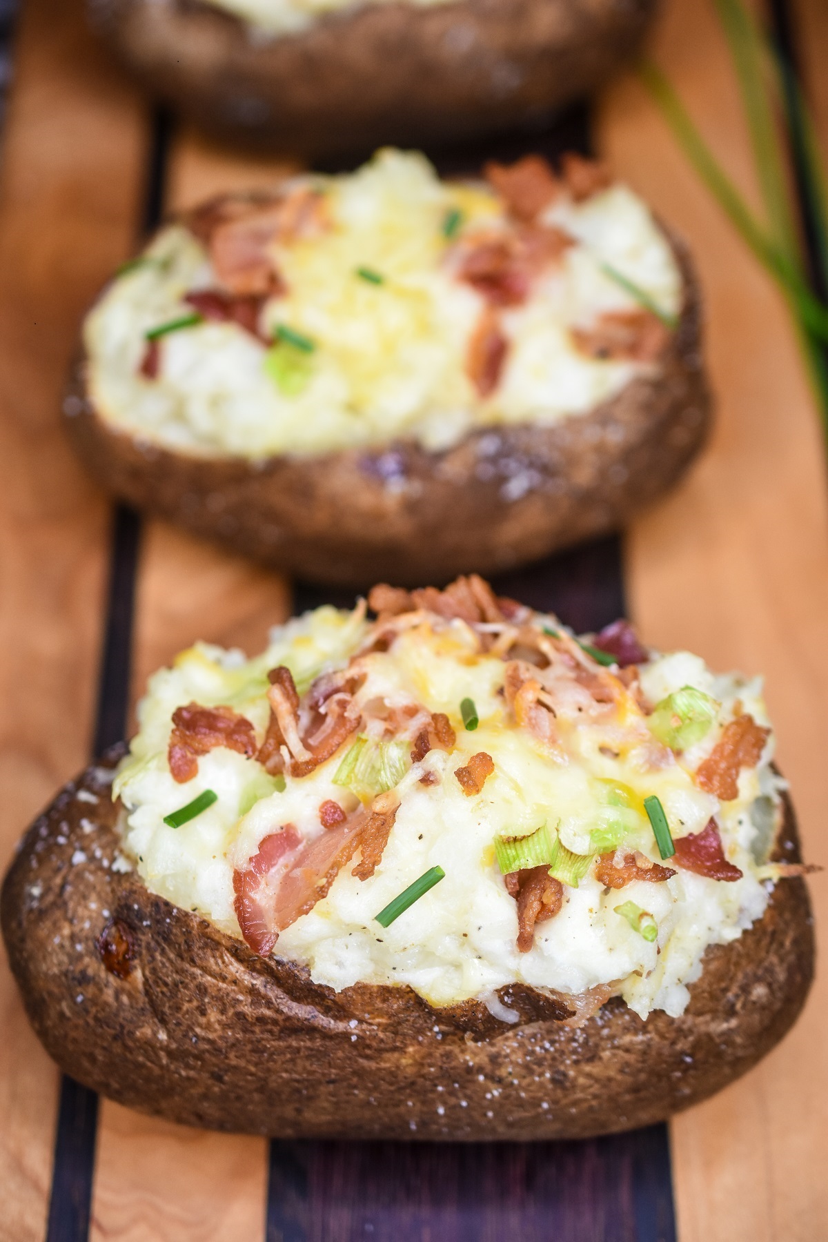 Twice Baked Potatoes are a fun and flavorful potato side dish recipe. Topped with bacon cheese and chives.