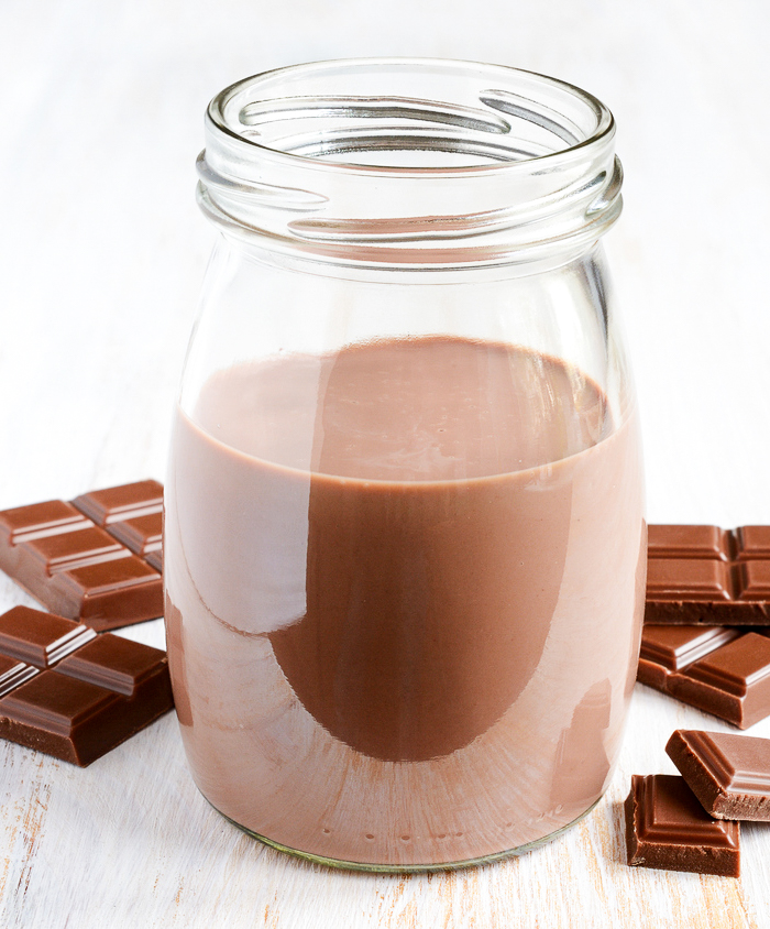 Hot cocoa stored in a mason jar with bars of chocolate alongside of it.