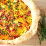 Mashed Potato Pizza Recipe shown as a whole mashed potato pie. Leftover mashed potatoes in pizza crust baked topped with cheese, bacon and chives.