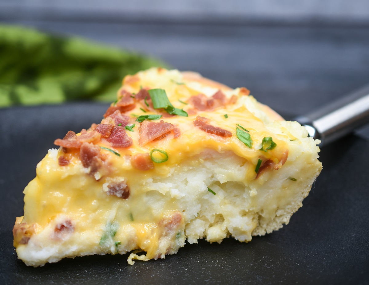 a slice of Mashed Potato Pizza Pie, its so delicious Mashed potatoes in a pizza crust topped with cheese, bacon and chives.