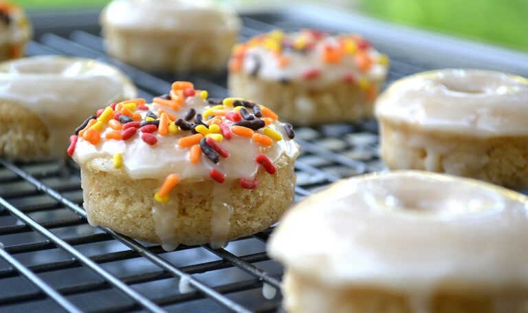 Baked Apple Cider Donuts on a baking rack. Dipped in Apple Cider glaze, some garnished with fall colored sprinkles