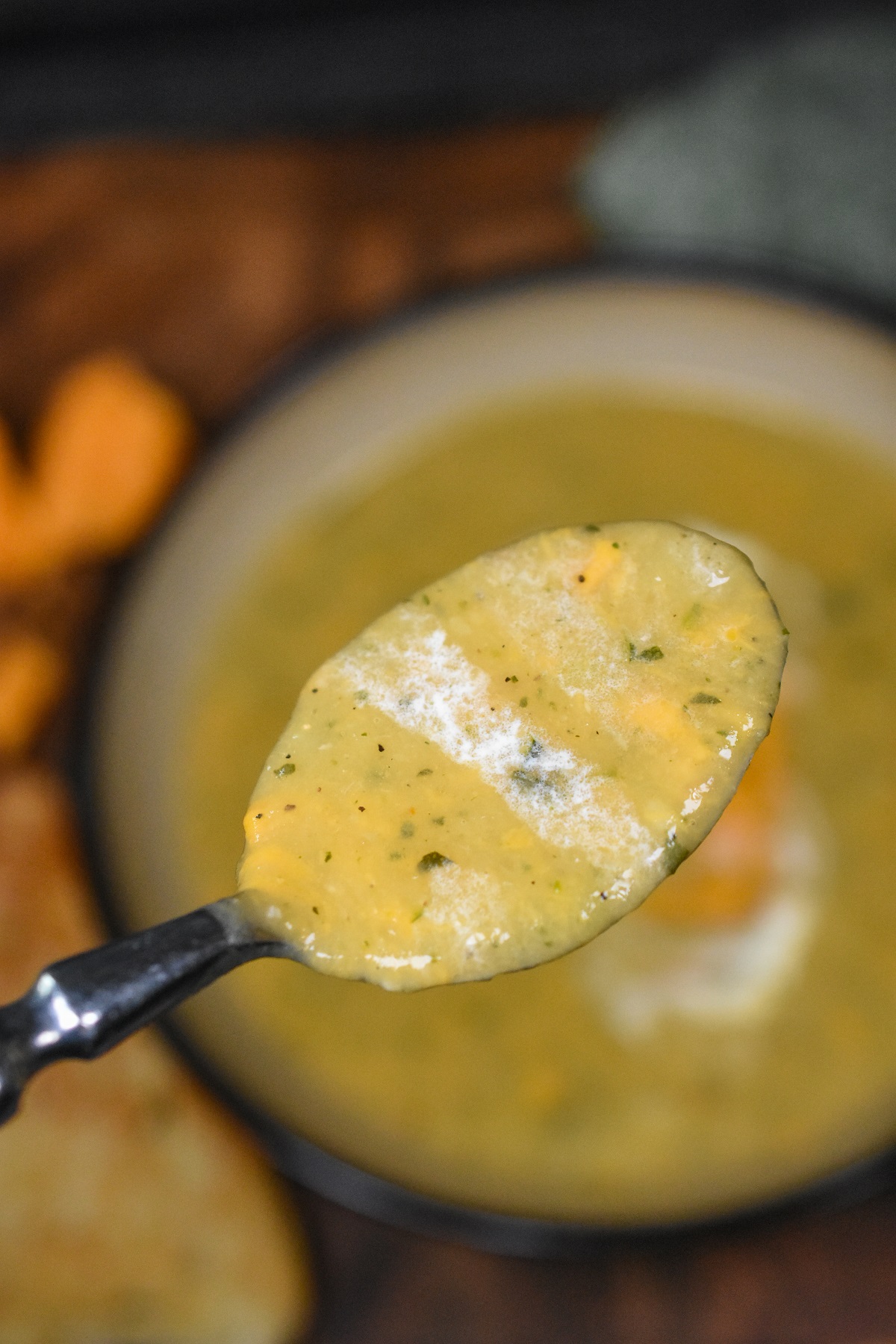 This Zucchini Soup has massive flavor and is so easy to make. It's a zucchini and cheese soup. You can add cream or not, delicious both ways. Shown a spoon full of soup held over the bowl