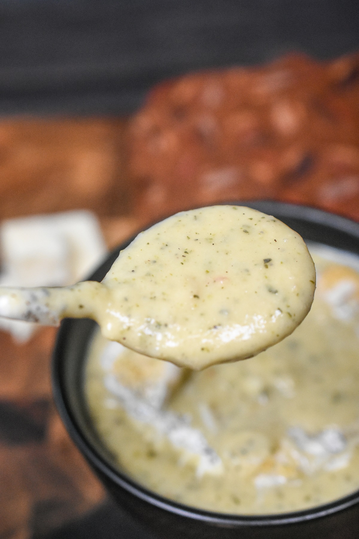 Recipe for Zucchini Soup. Zucchini Cheese Soup shown on a spoon over a black bowl