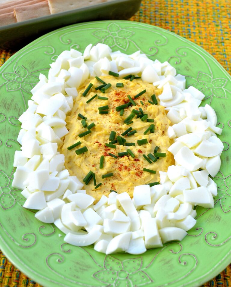 Giant Deviled Egg Appetizer recipe. Deconstructed Deviled Egg shown on a green plate. Diced egg whites with deviled egg filling center.