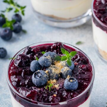 Cheesecake Parfait, Blueberry Cheesecake Shooters dessert. Shown in small glass cups garnished with fresh blueberries.