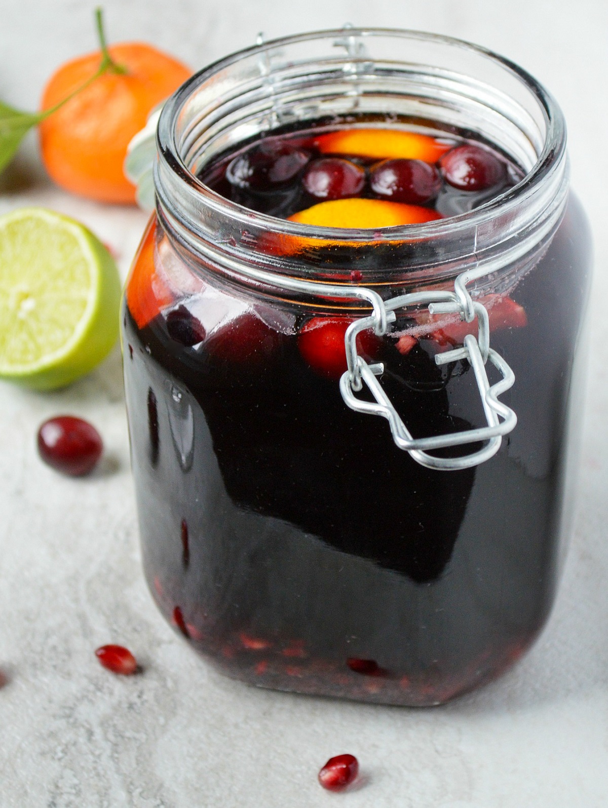 Winter Sangria recipe is a great holiday drink recipe and food gift too. Also called Christmas Sangria, shown in a glass jar garnished with satsumas, cranberries and pomegranates 