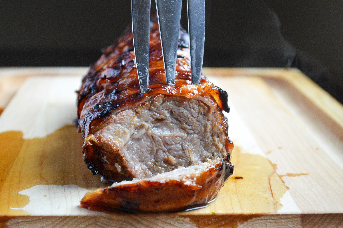 Grilled Bacon Wrapped Pork Tenderloin on a wood cutting board