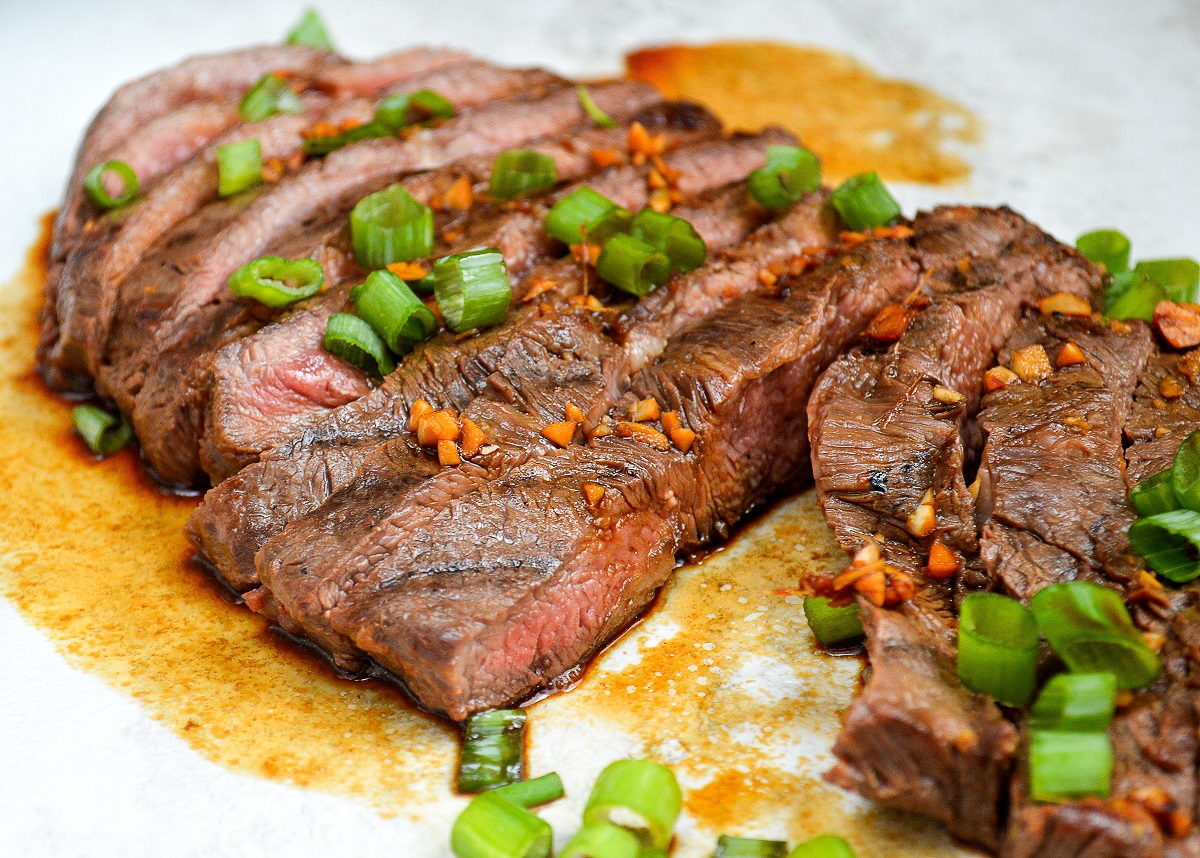 Grilled Flat Iron Steak cut into slices with scallions