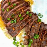 Grilled Flat Iron Steak shown sliced into pieces with scallions