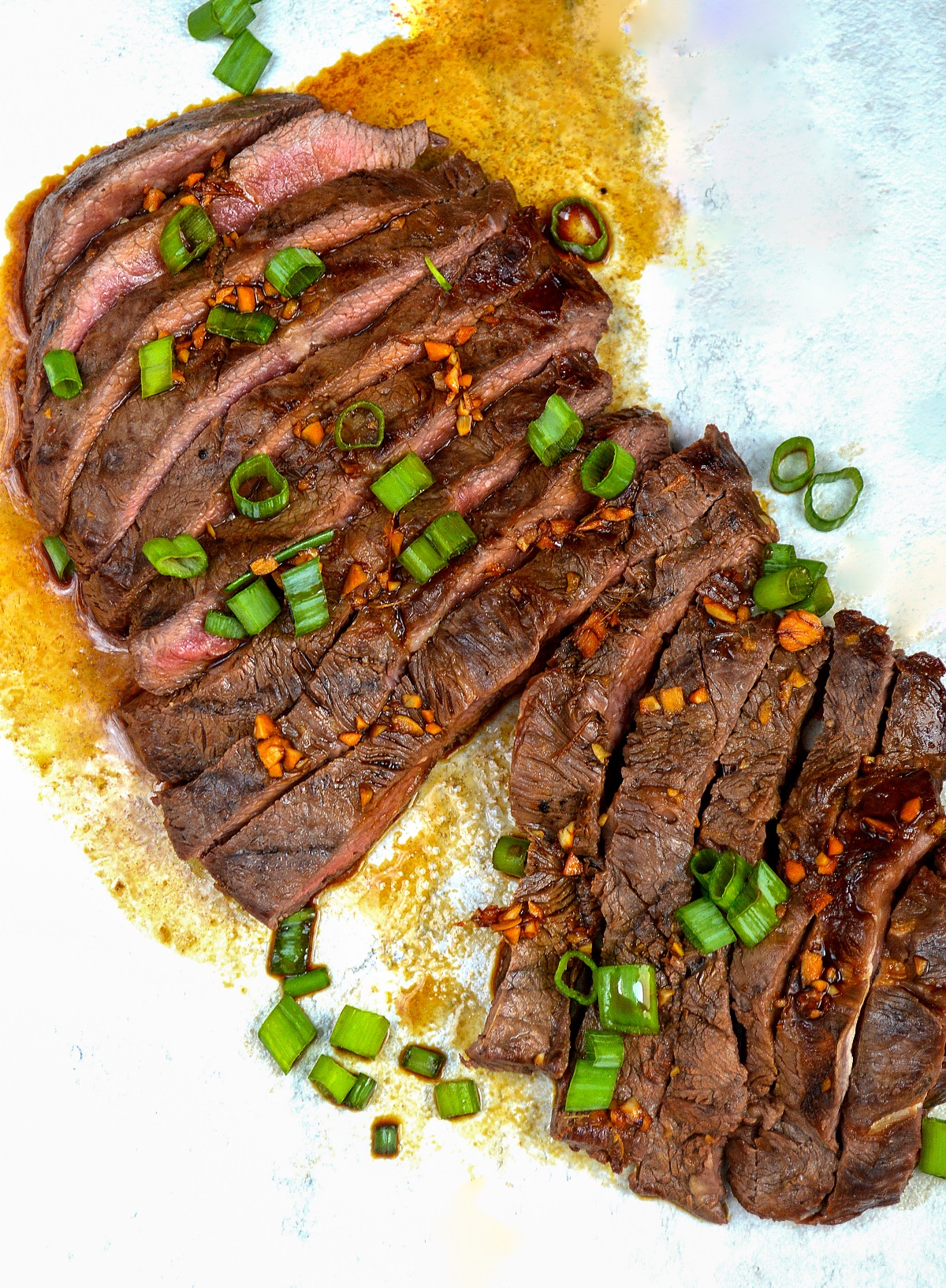 Grilled Flat Iron Steak shown sliced into pieces with scallions