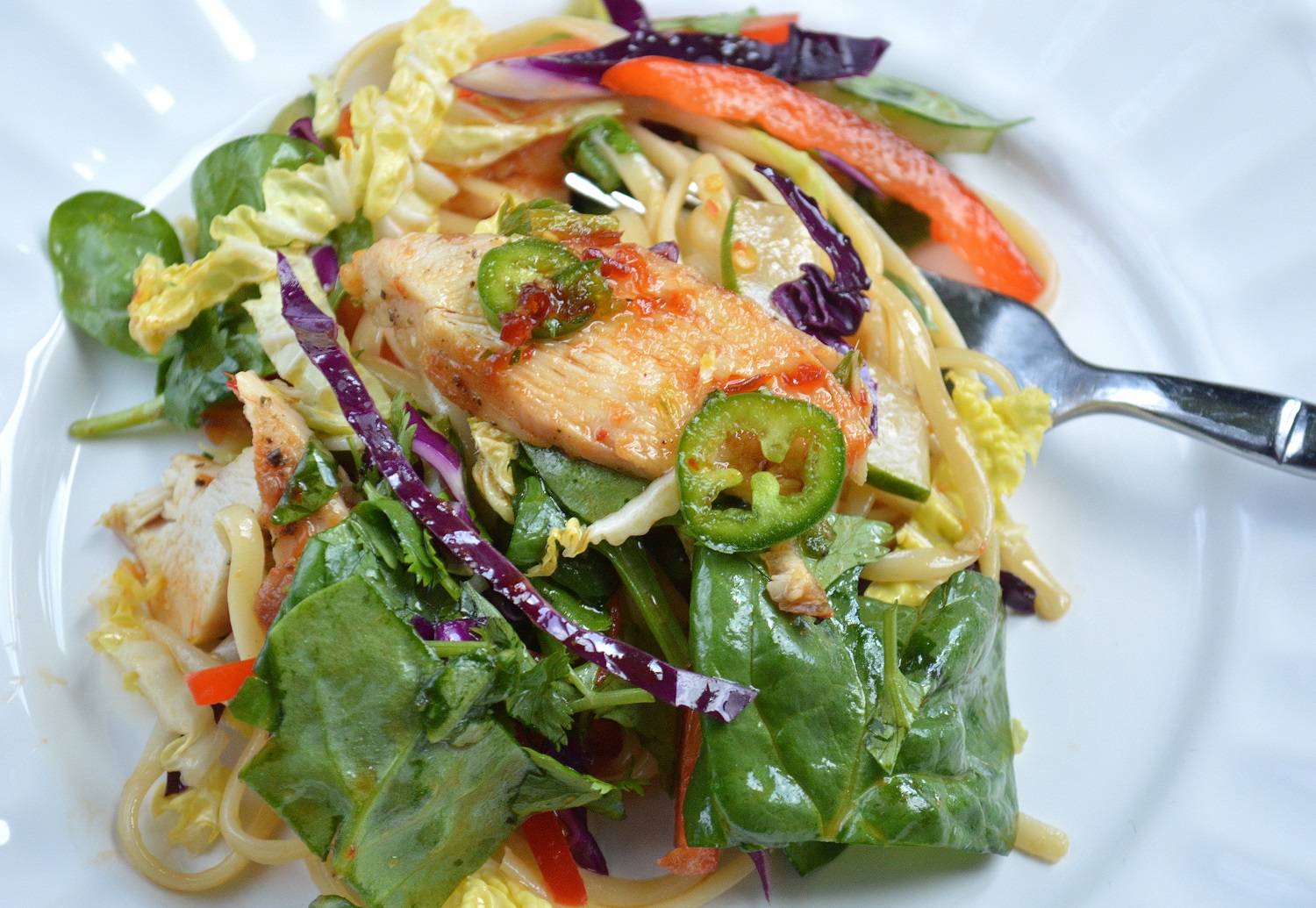 Asian Noodle Salad With Grilled Chicken shown on a plate with a fork.