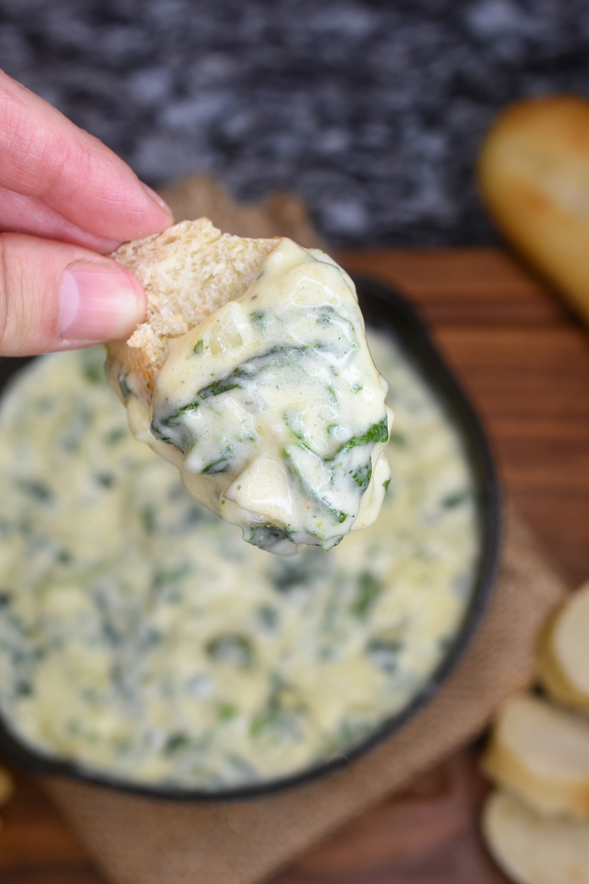 Hot Spinach Artichoke Dip made stovetop. No may dip. This is just as tasty as ordering it at a restaurant!! Shown in a small cast iron skillet with a slice of French bread dipped in.