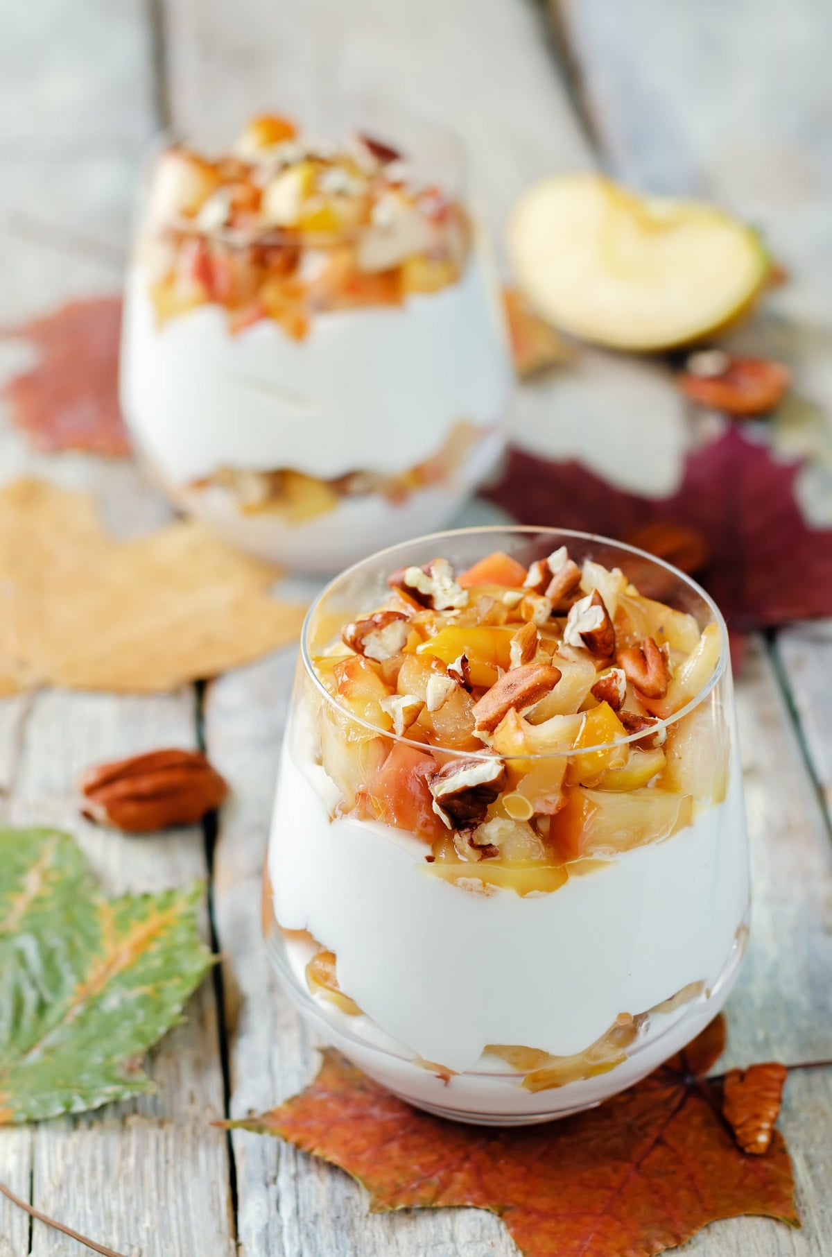 Apple Pie Cheesecake Dessert. A no bake cheesecake filling layered in a stemless wine glass with sautéed apples and nuts.