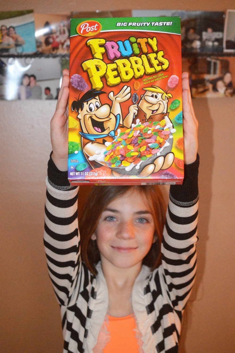 Young girl holding up a box of Fruity Pebbles