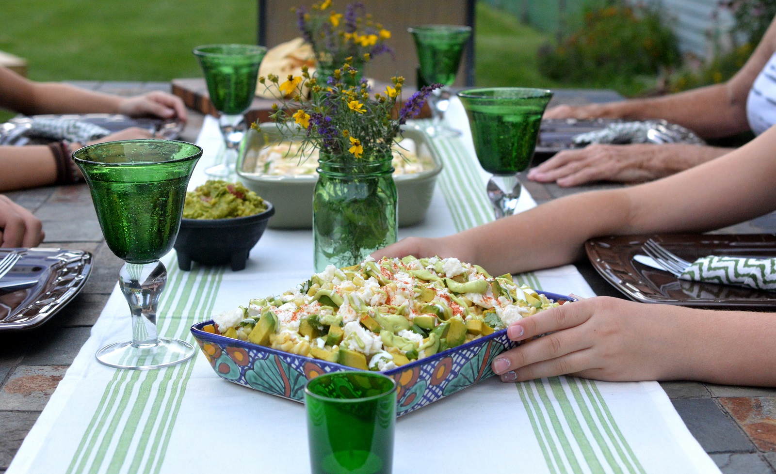 Mexican Street Corn Salad set on a table with chicken enchiladas and flowers