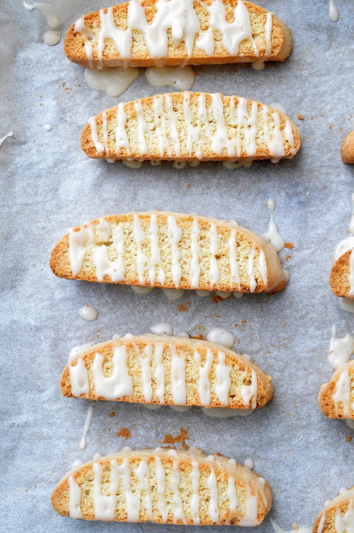Homemade Apple Cider Biscotti on a parchment paper lined baking sheet glazed with apple cider drizzle