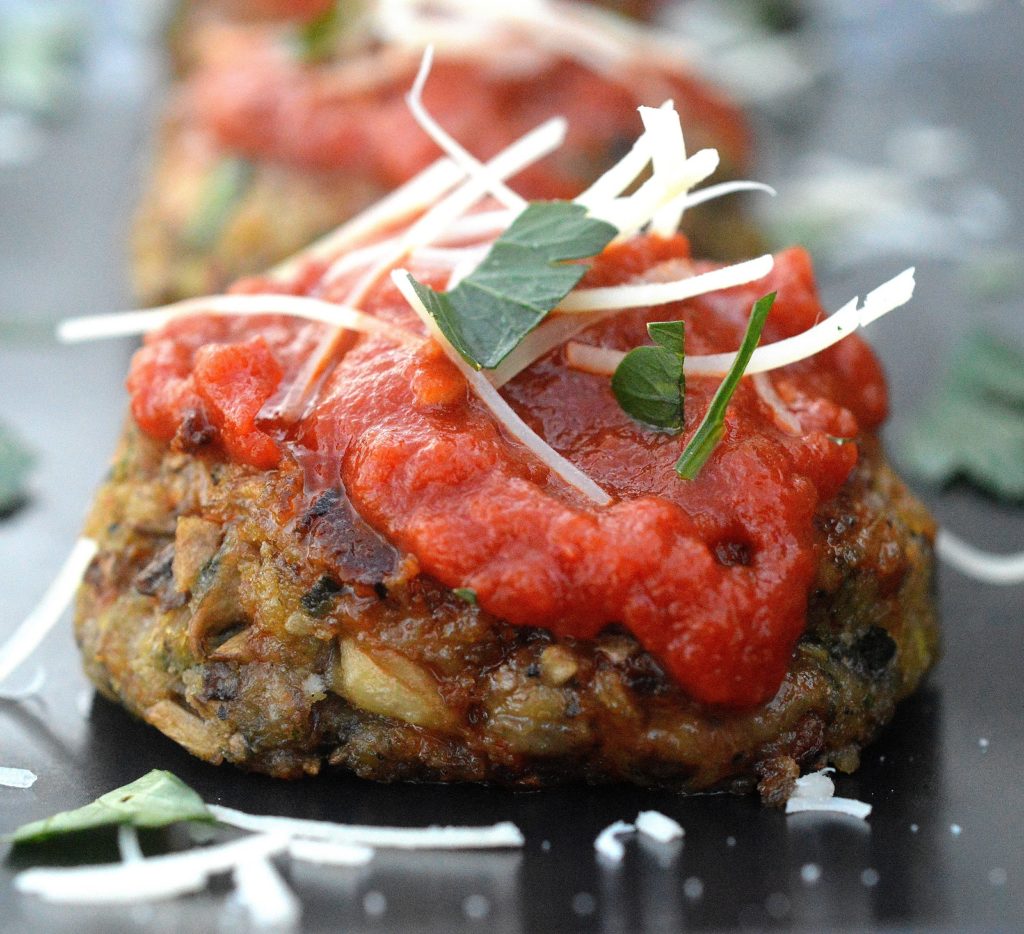 Cheesy Mushroom Meatless Meatballs on a black plate topped with red sauce