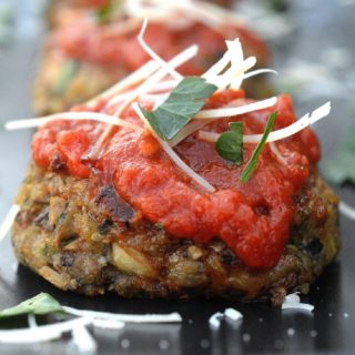 Cheesy Mushroom Meatless Meatballs on a black plate topped with red sauce