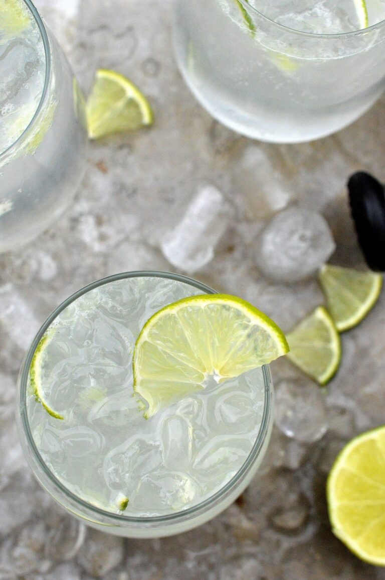 Low Carb Vodka Cooler Drink. Shown glasses fill of ice and lime vodka drink with lime wedge on a metal tray with ice cubes.
