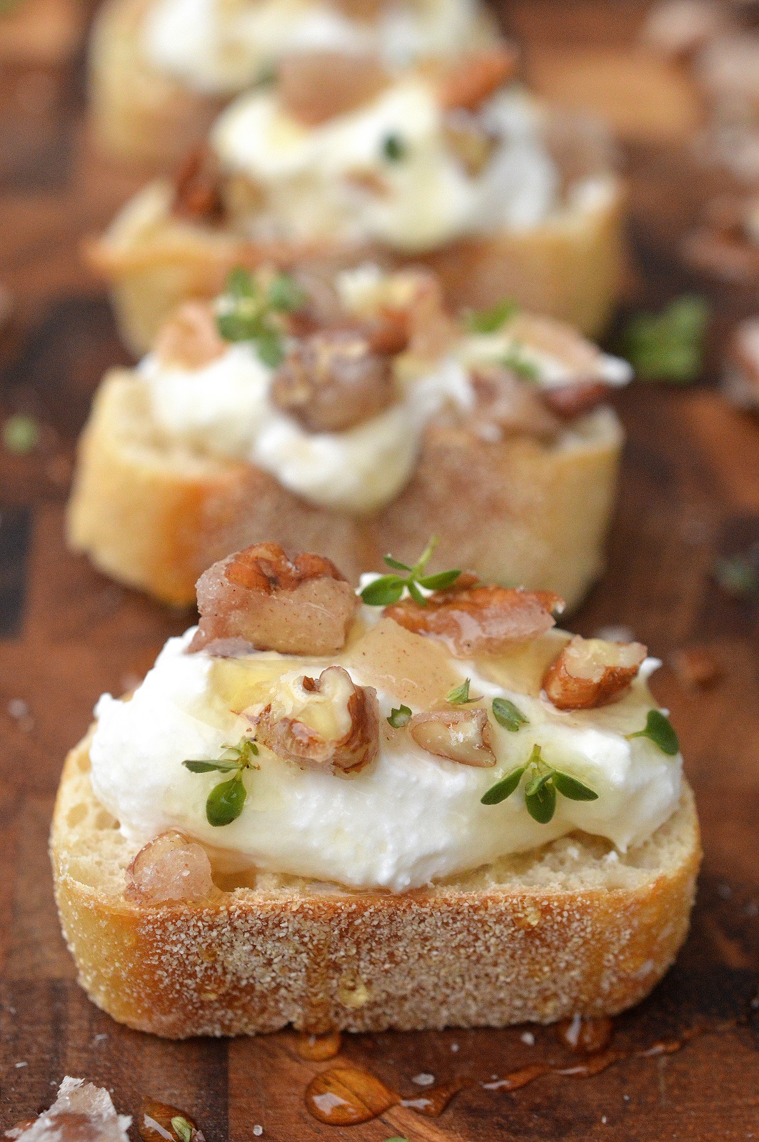 Whipped Ricotta Crostini with candied nuts. Crostini with ricotta garnished with nuts, honey and herbs.