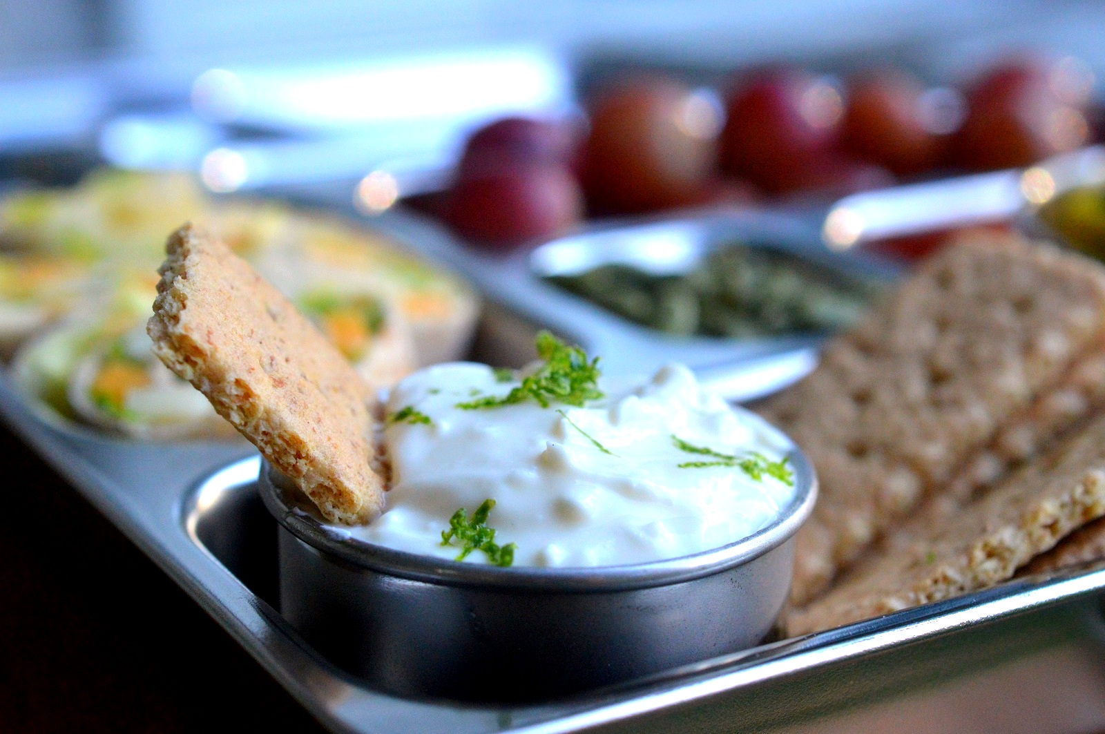 Easy Key Lime Pie Dip shown in a lunch box with a graham cracker for dipping