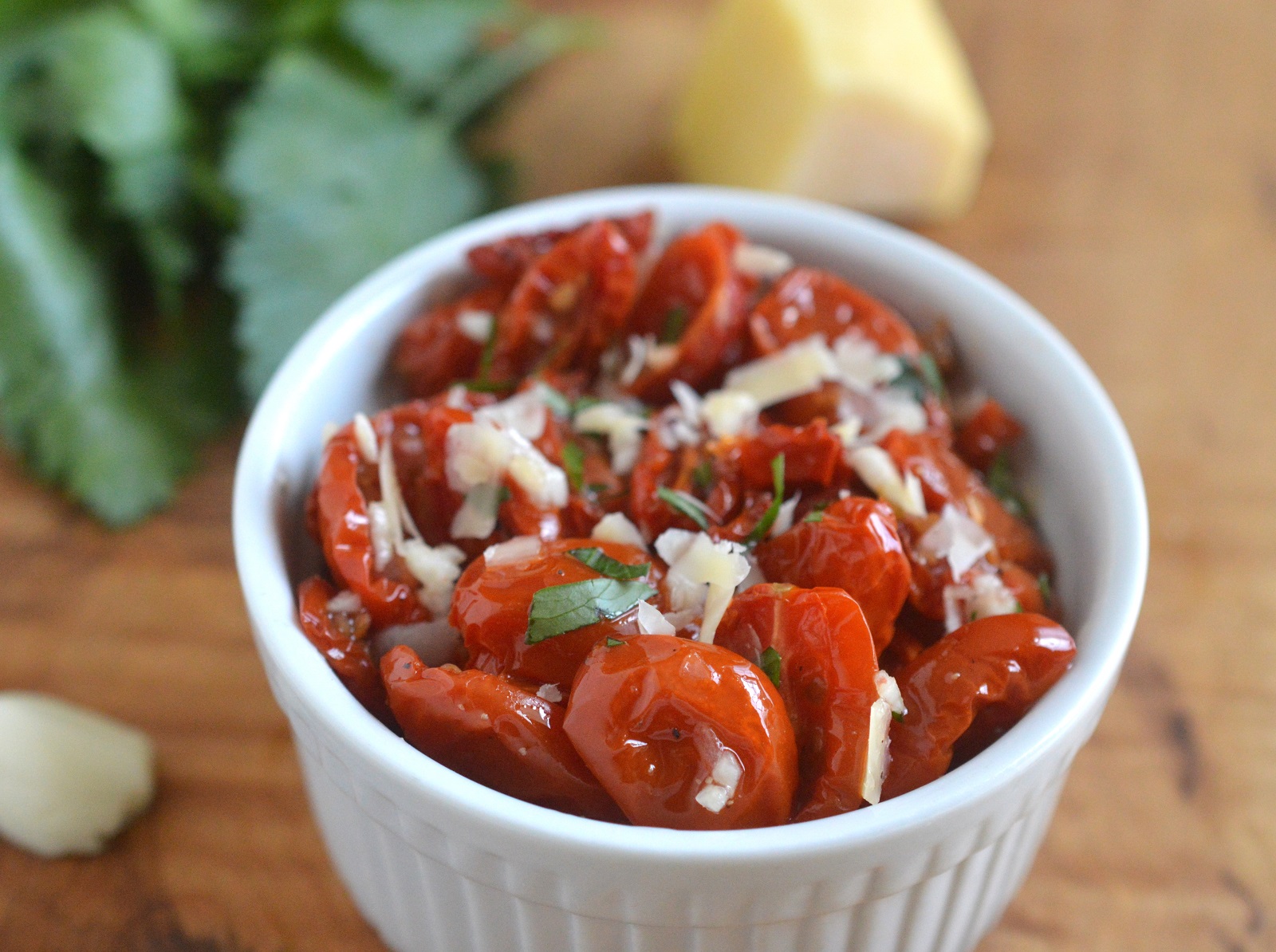 Homemade Sun-Dried Tomatoes shown in white ramekin with Parmesan cheese