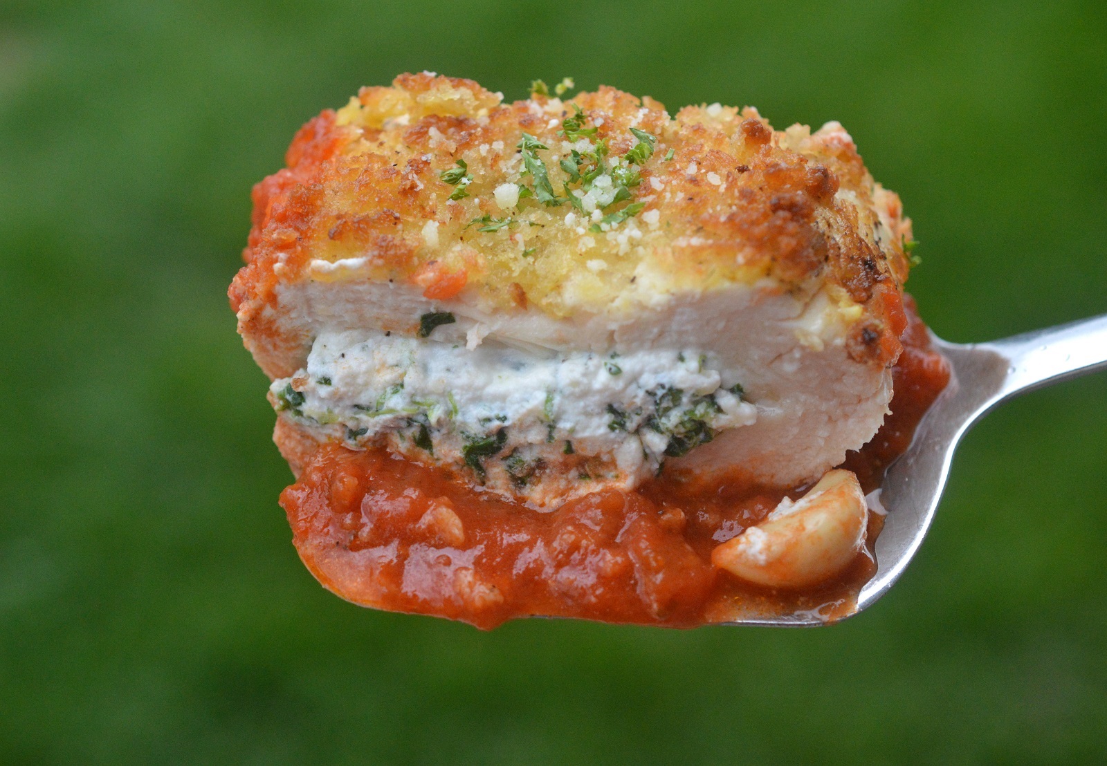 Lasagna Stuffed Chicken Breasts with Spinach. A slice shown on a spatula. Crispy outside, ricotta stuffed chicken inside.