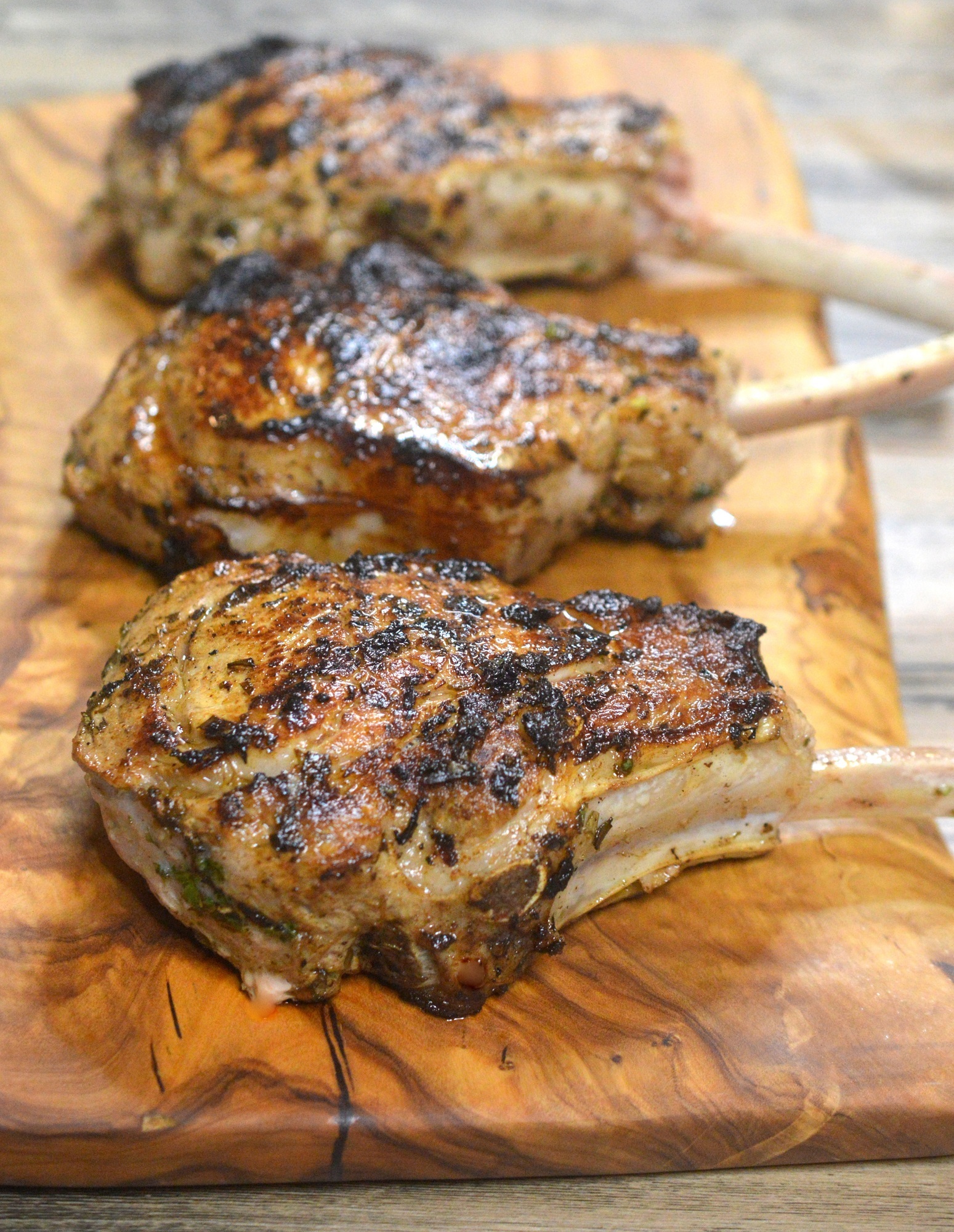 The BEST Grilled Veal Chops Recipe Shown Grilled Veal Chops on a wooden board.