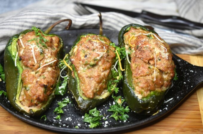 Cooked Grilled Meatloaf Stuffed Peppers on a cast Iron skillet garnished with parsley