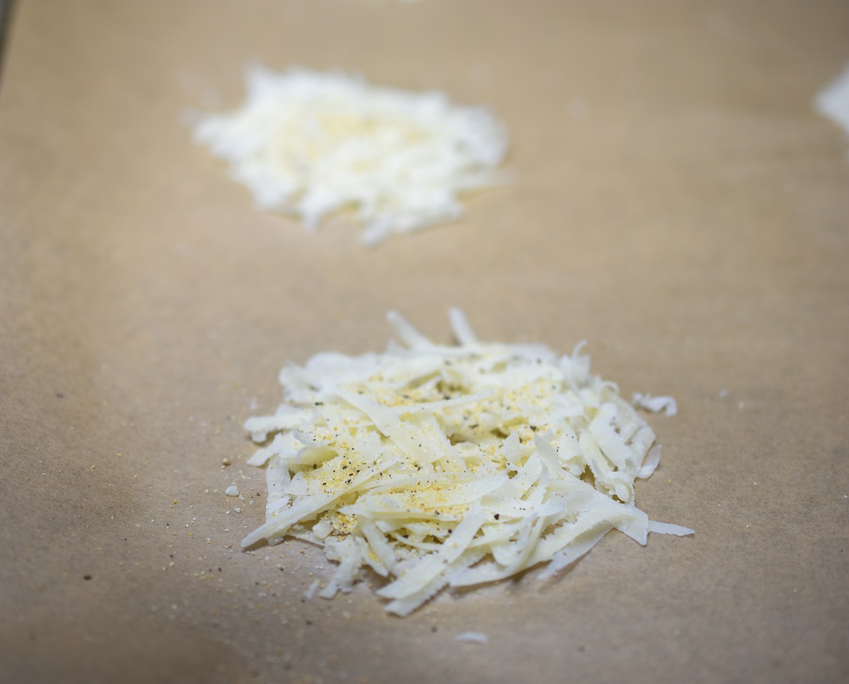 Parmesan Cheese Crisps shredded on parchment paper lined baking sheet to make cheese crisps