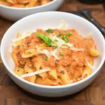 Vodka Penne Recipe. Homemade vodka sauce recipe over penne in two white bowls garnished with fresh Parmesan and basil
