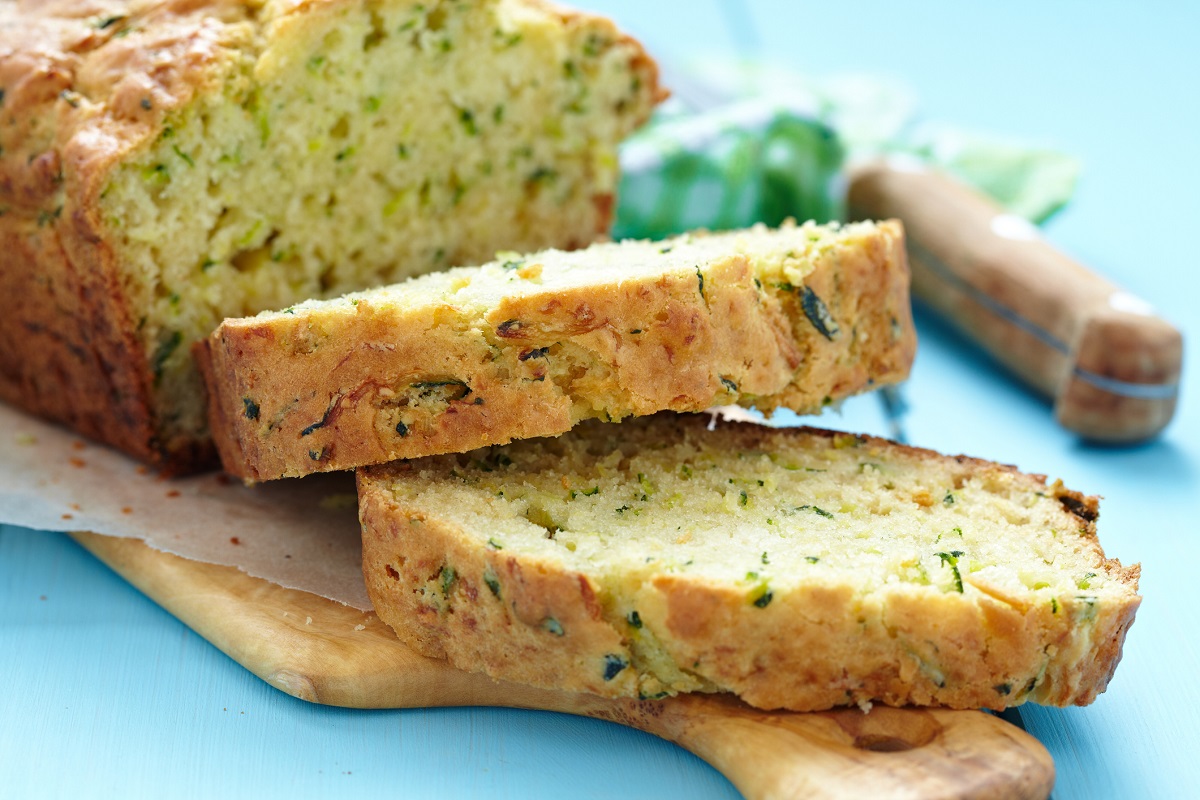 Savory Zucchini Bread cut into slices on a wood cutting board.
