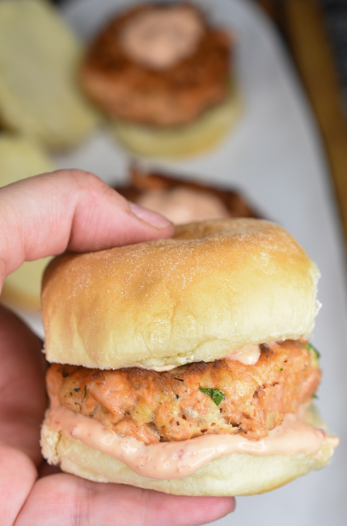 Salmon Sliders Salmon burger on a roll with sriracha mayo