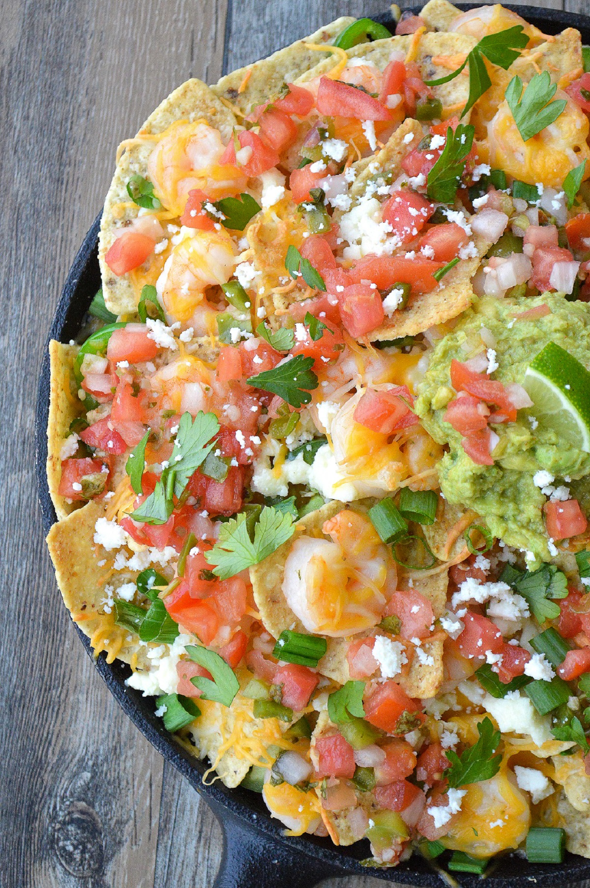 Shrimp Nachos recipe Platter of nachos topped with shrimp, tomatoes, cheese, scallions and more.