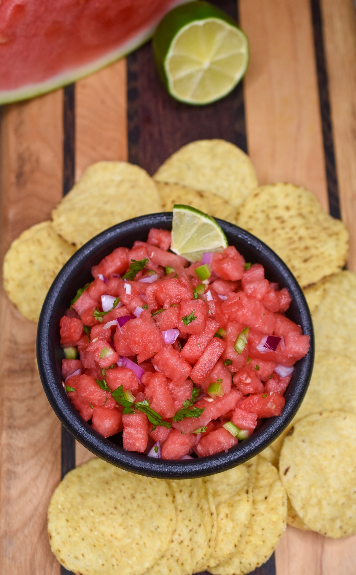 Watermelon Salsa shown in a black salsa bowl surrounded by tortilla chips