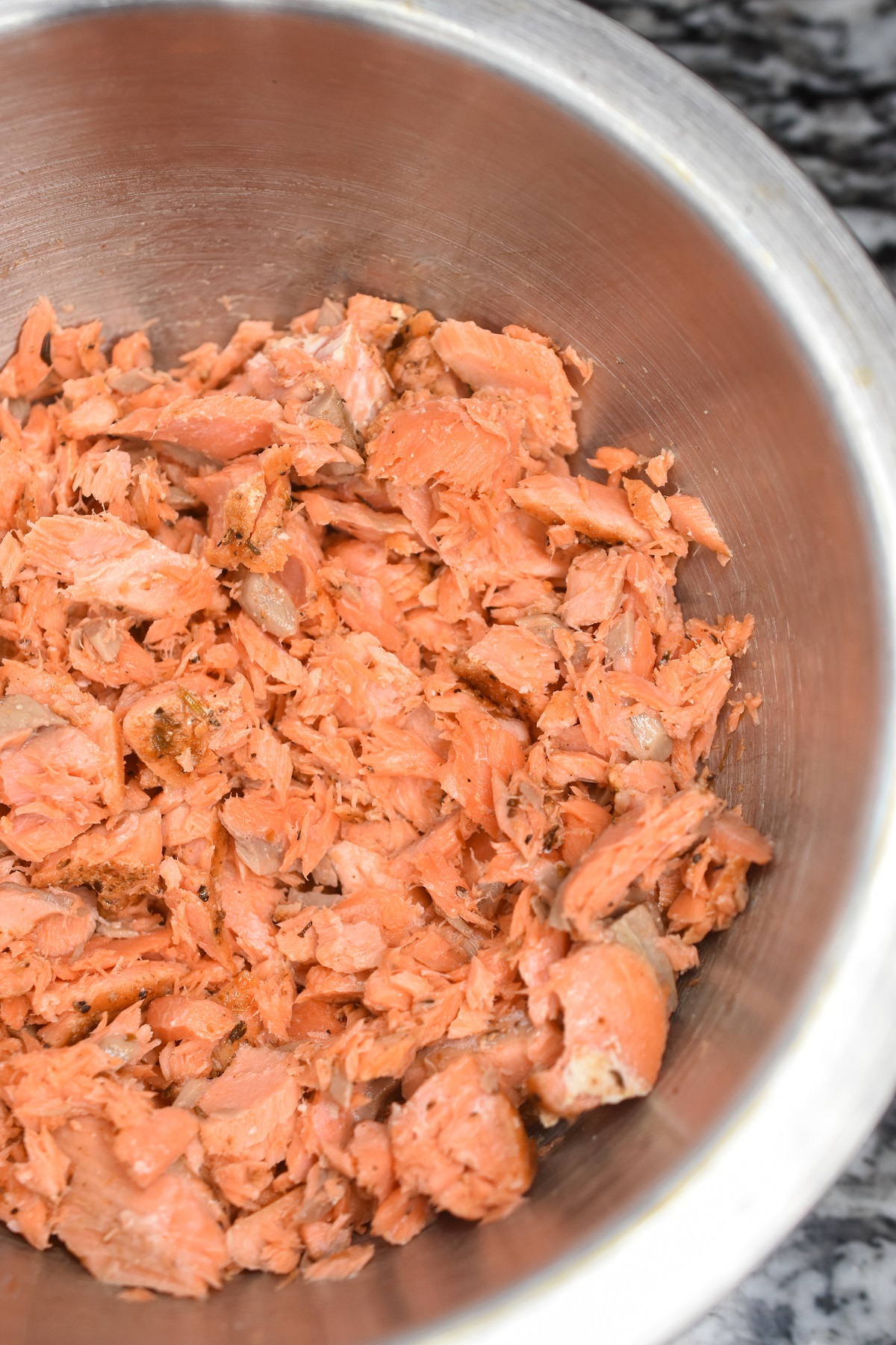 Flakes cooked salmon in a bowl to make Salmon Sliders