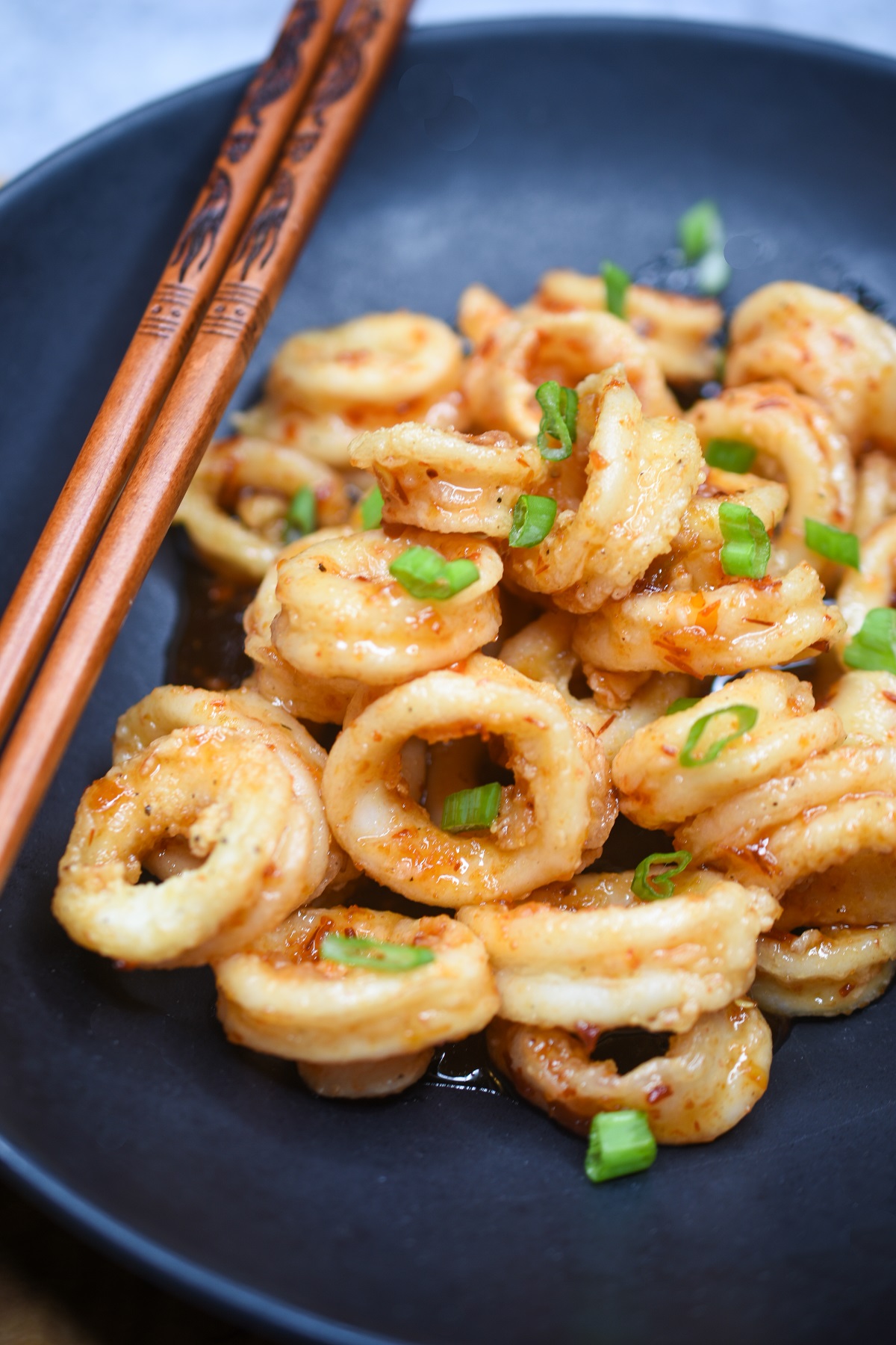 Fried Calamari Recipe. Sweet & Spicy Calamari. Thai Calamari shown on a plate with chopsticks garnished with scallions.