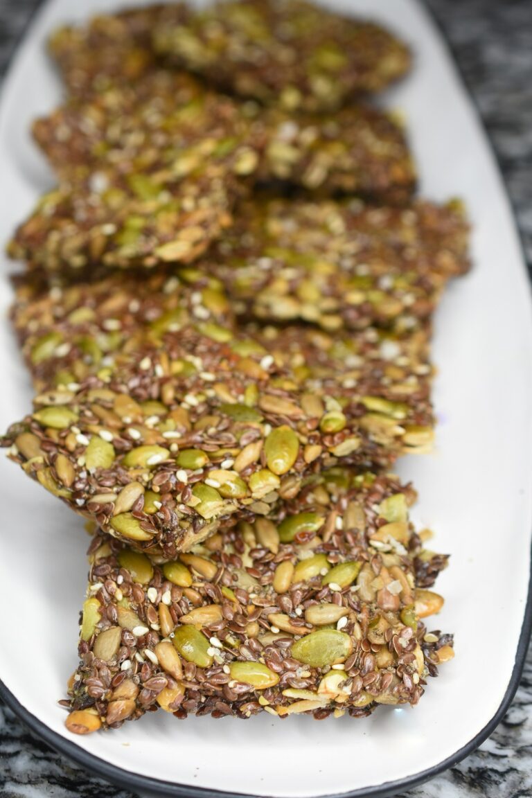 How to make seed crackers. Easy recipe for flourless crackers. Seed crackers made of sunflower seeds, pumpkin seeds, flax seeds, chia seeds and sesame seeds. Shown on white plate.