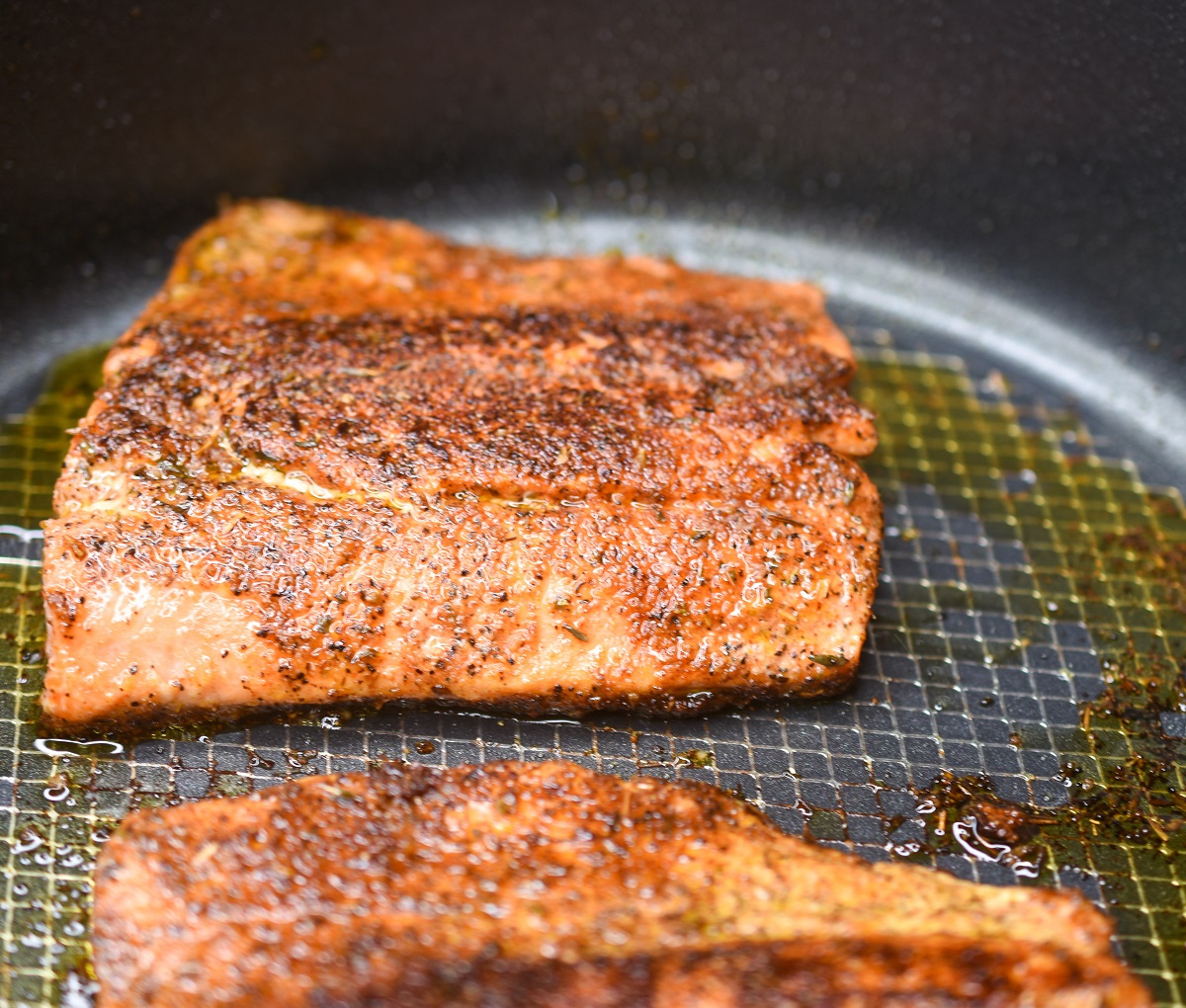 Blackened salmon cooking in a pan for salmon rice bowls