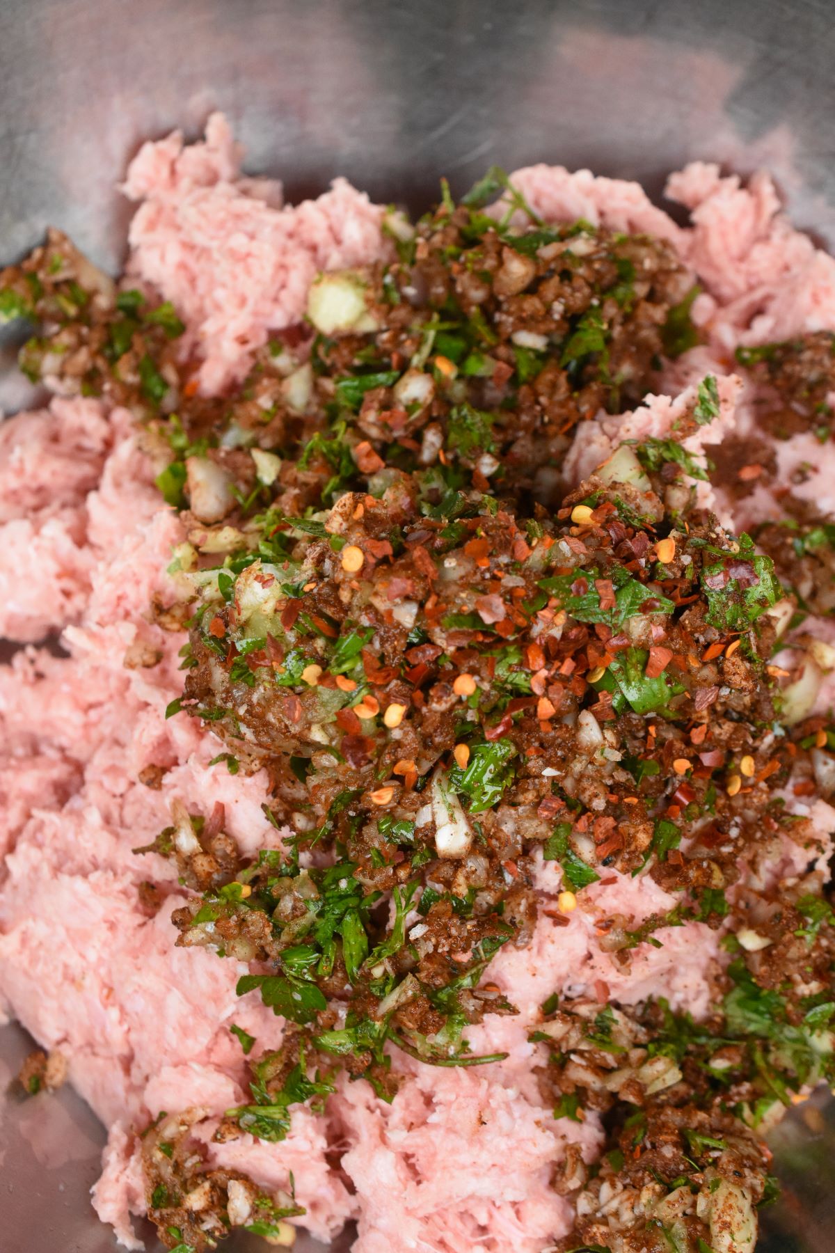 Spice mixture and ground meat for making Kofta in a metal bowl