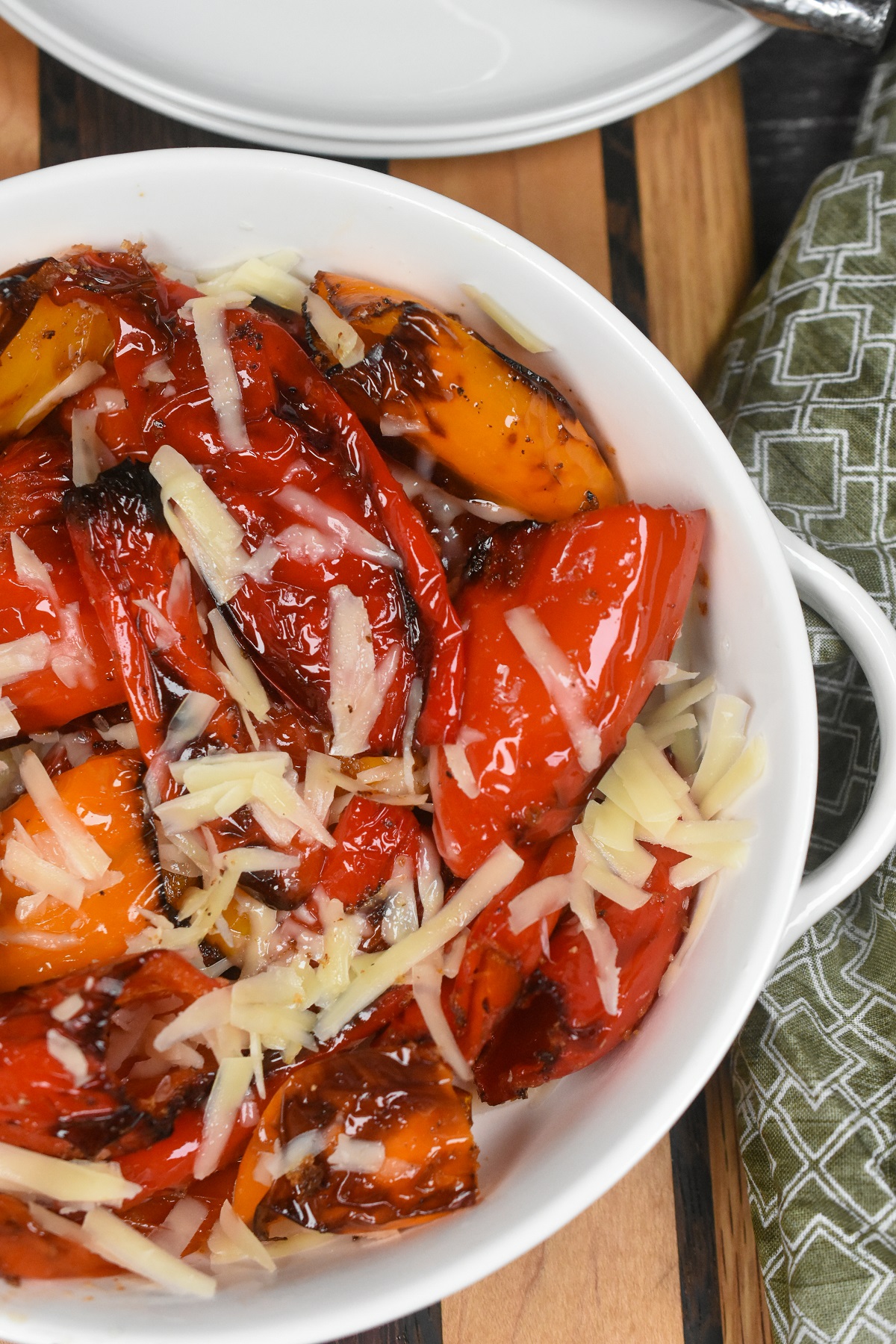 Air Fryer Peppers. Shown in white bowl are air fried peppers (red, yellow and orange), charred and topped with freshly shredded parmesan cheese.