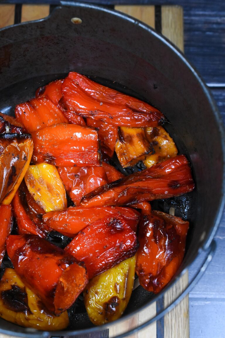 Air Fryer Peppers. Mini Sweet Peppers in Air fryer. red, yellow and orange mini peppers charred from air fryer in cooking basket.
