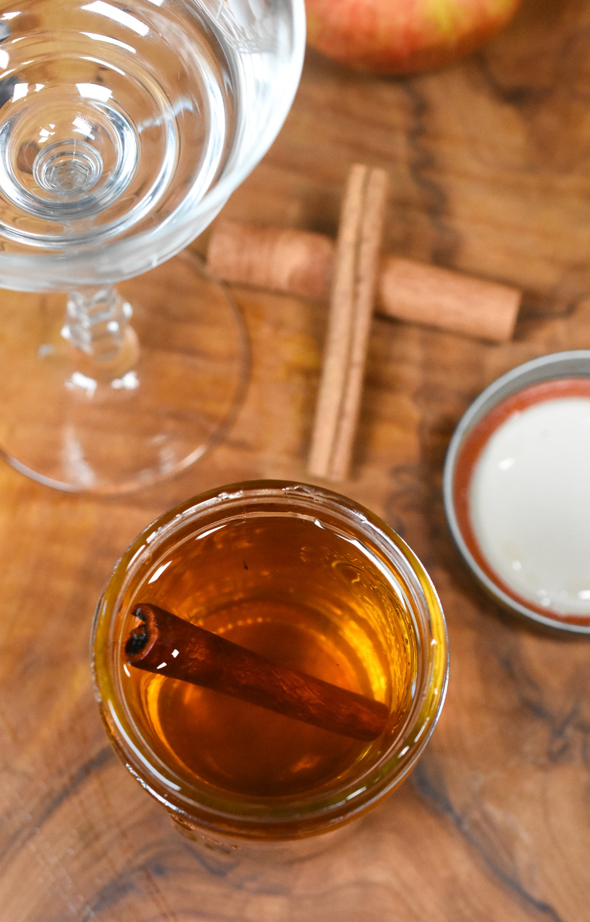 Homemade Cinnamon Syrup shown in a mason jar with a cinnamon stick. For making fall cocktails.