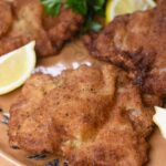 Weiner Schnitzel Shown cooked on a large platter, 4 peices of Weiner Schnitzel made with veal garnished with lemon wedges and parsley