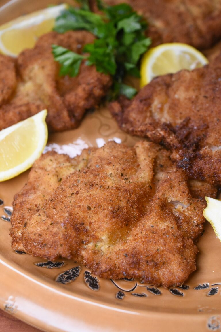 Weiner Schnitzel Shown cooked on a large platter, 4 peices of Weiner Schnitzel made with veal garnished with lemon wedges and parsley