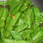 snow peas recipes shown sauteed snow peas in a grey pan cooked with garlic and red pepper flakes