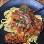 ragout over pappardelle on black plate