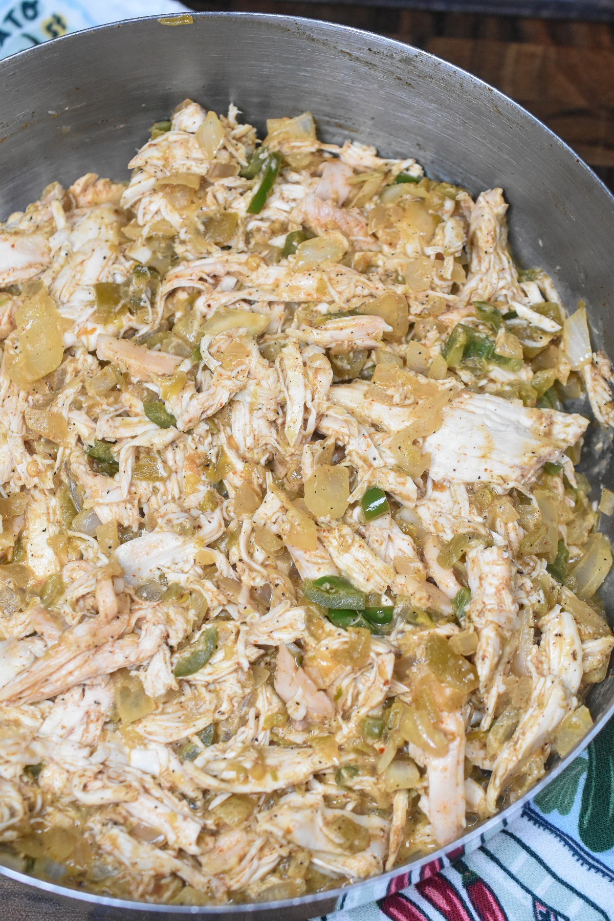 filling for white chicken enchiladas, shredded chicken in a bowl mixed with jalapenos, chilies and salsa verde.