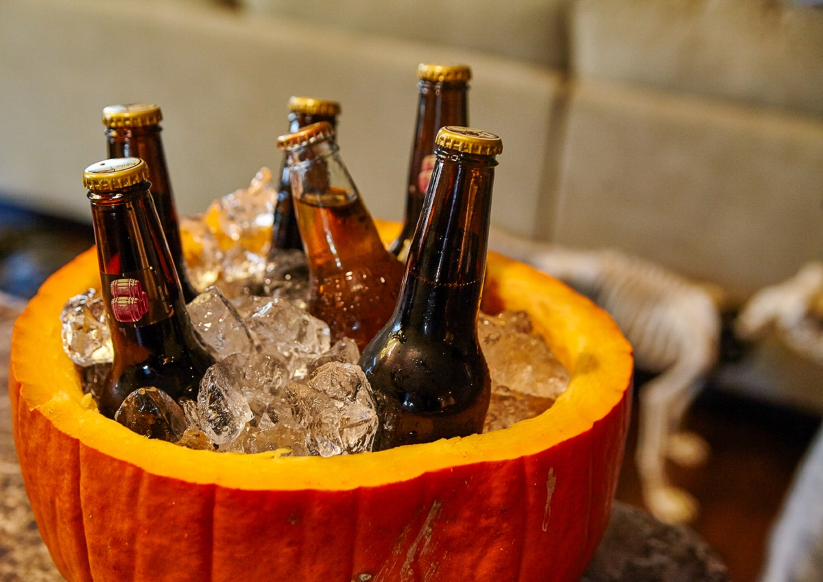 a fresh pumpkin cut in half being used a s an ice bucket for bottled drinks